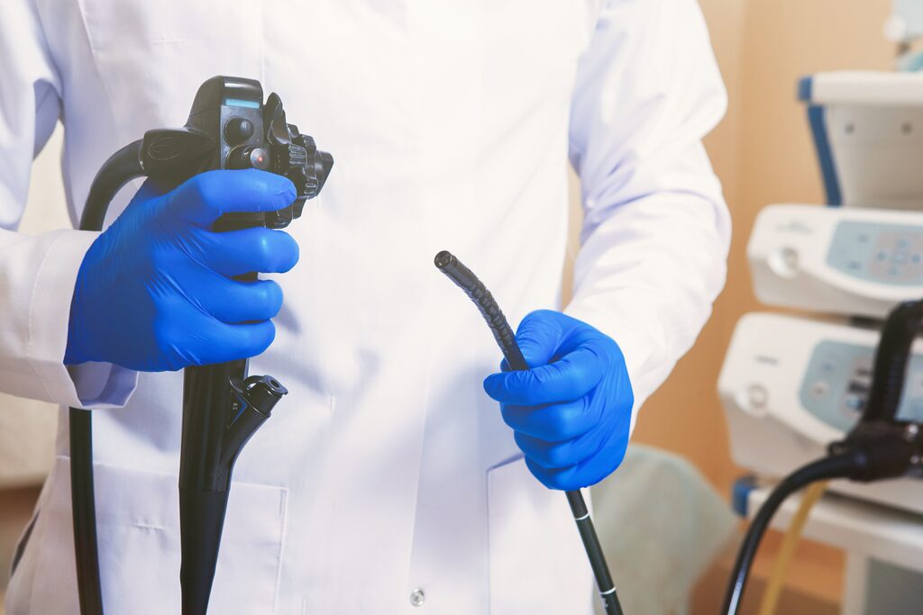 Clinician holding an endoscope and insertion tube in a treatment room
